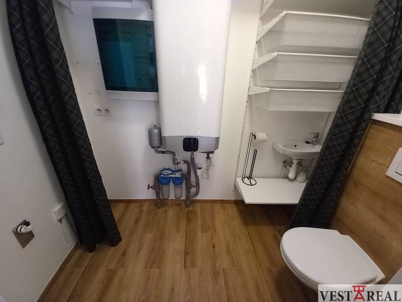 A bathroom in a family house with a boiler, sink, toilet, and practical storage solution.