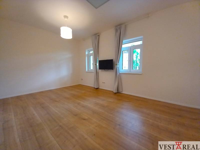 A spacious room with wooden flooring and a television in a family house.