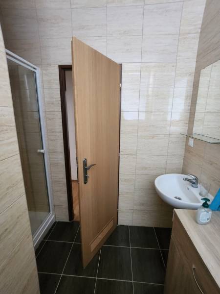 A bathroom in a building with tiles, a sink, and a shower.