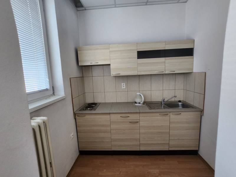 Kitchen unit in a building with a window, cabinets, and a cooktop.
