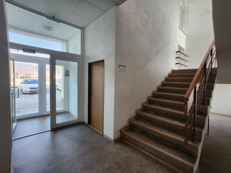 Staircase and glass entrance door in a building with a view of the parking lot.