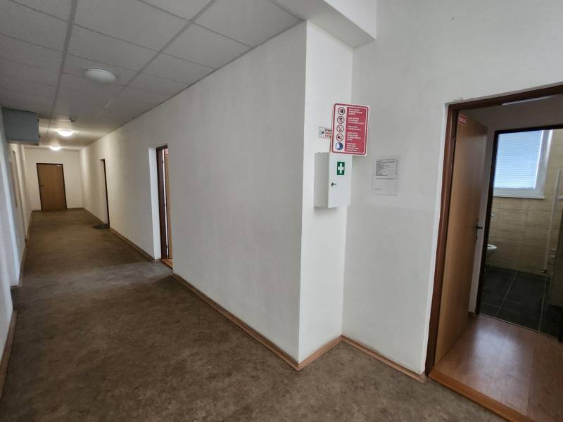 A corridor with multiple doors, light walls, and a floor. Part of a building.