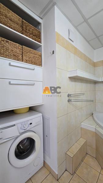 Bathroom with a washing machine and storage baskets in a 2-room apartment.