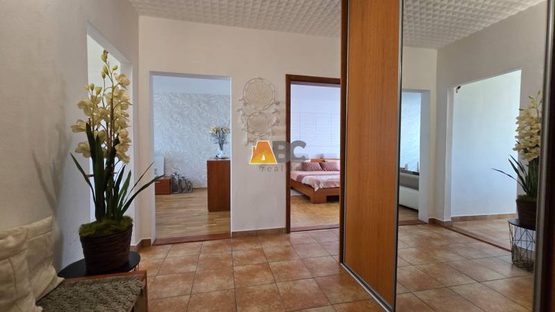 A hallway in a 2-room apartment with flowers and a view of the bedroom.