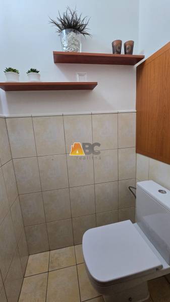A toilet in a 2-room apartment with shelves and plants.