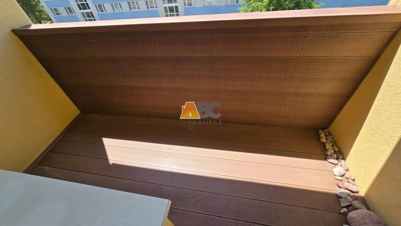 Comfortable balcony with wooden flooring and pebbles in Zvolen, 2-room apartment.
