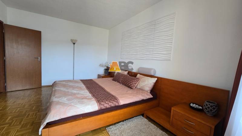 A bedroom in a two-room apartment with wooden furniture and a large bed.