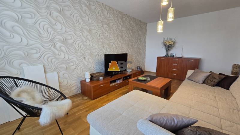 Living room in a 2-room apartment with a bold wall pattern, sofa, and wooden furniture.