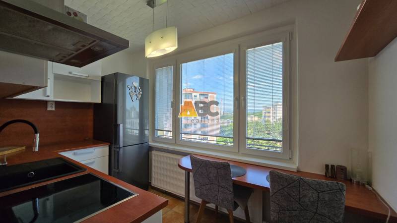 Kitchen in a 2-room apartment with windows, a refrigerator, a stove, and dining seating.