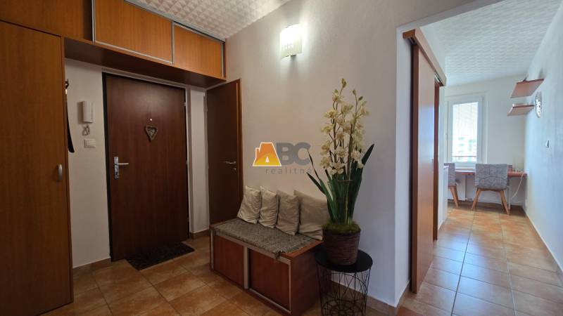 Entrance hallway in a 2-room apartment with wooden furniture and floral decoration.