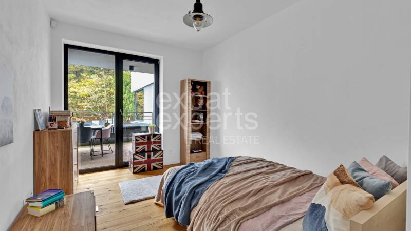 A bedroom in a family house with a balcony, wooden flooring, and cozy furnishings.