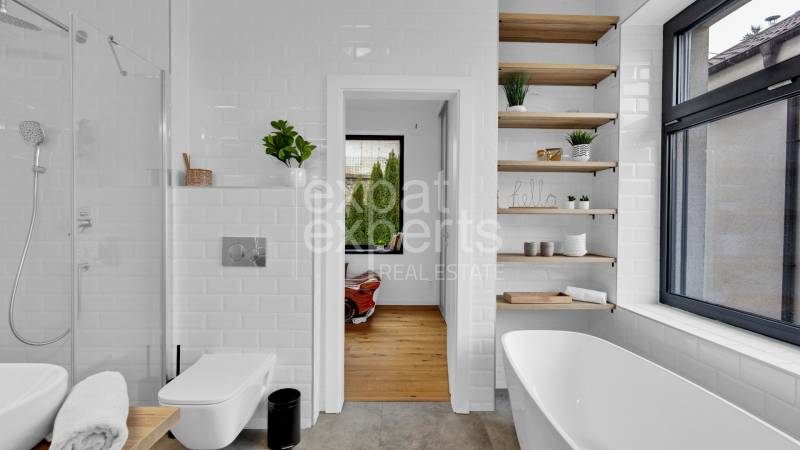A bathroom in a family house with a bathtub, shower, and open shelves.