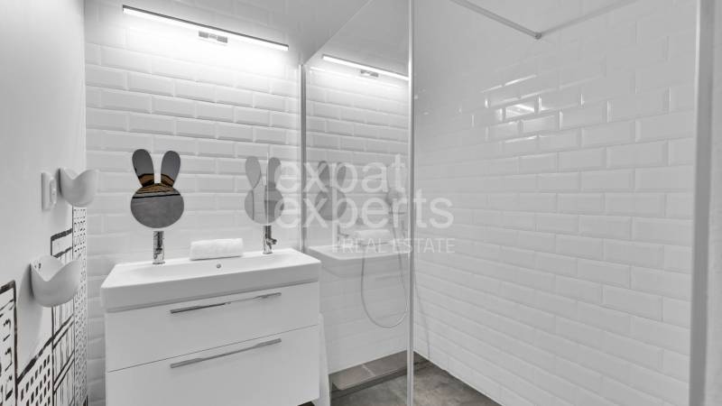 A bathroom in a family house with a sink, a shower, and ceramic tiles.
