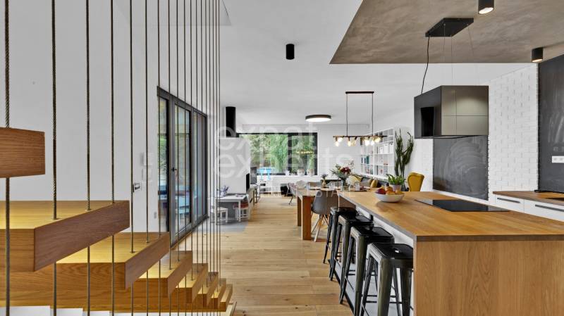 Staircase and open kitchen with an island and bar stools in a family house.