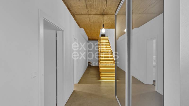A hallway with a lit staircase and a mirror in a family house.