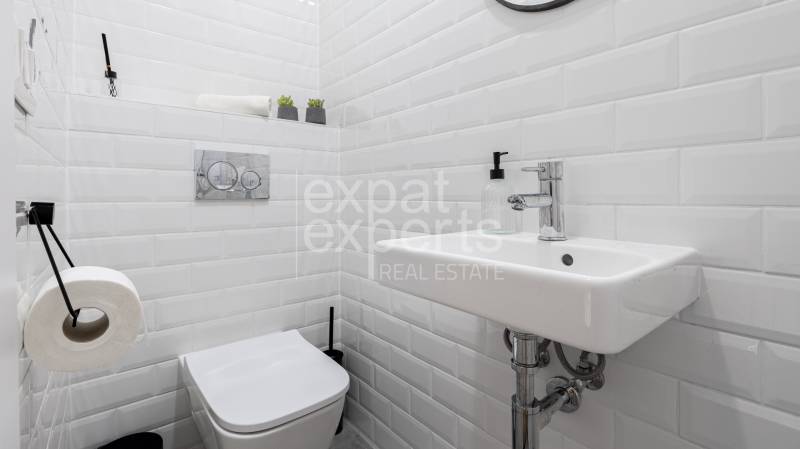 A small bathroom in a family house with white tiles, a sink, and a toilet.