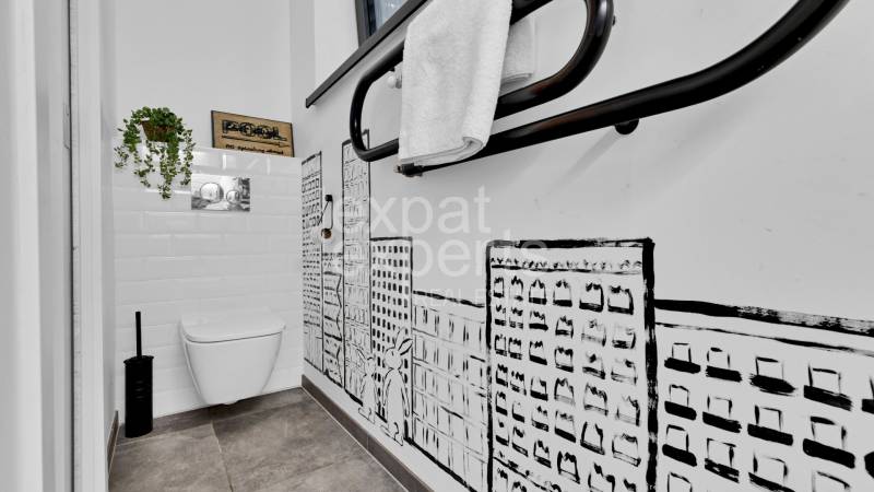 Bathroom with toilet in a family house, tiled walls and graphic wall decor.