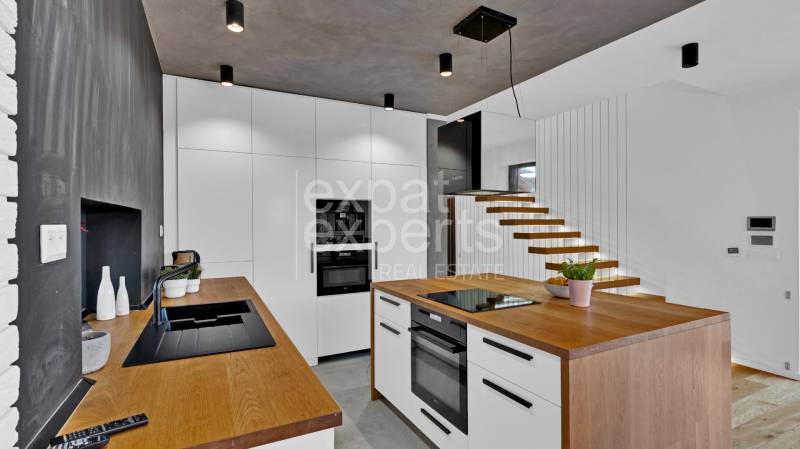 A kitchen in a family house with modern furniture and a minimalist staircase design.