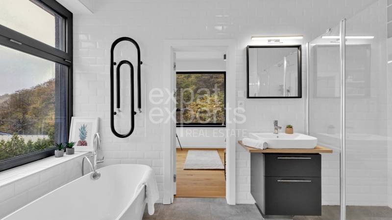 A bathroom in a family house with a bathtub, a sink, and a view of nature.