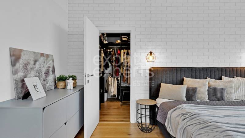 Bedroom of a family house with an open wardrobe, bed, and decorations on the dresser.