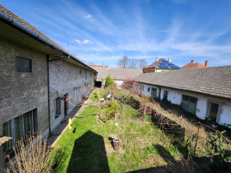 A courtyard with older buildings and vegetation in Nové Mesto nad Váhom on P. O. Hviezdoslav Street.