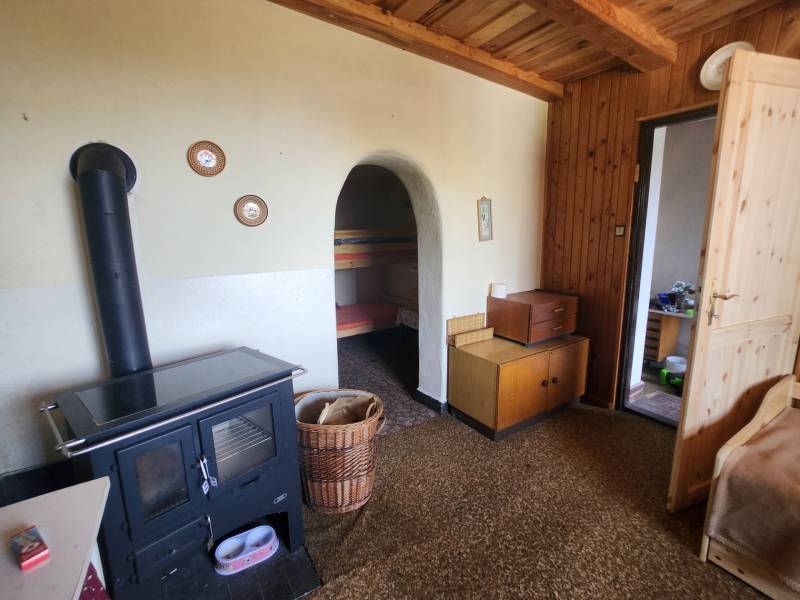 Wood-burning stove, wooden furniture, and bed in the cabin.