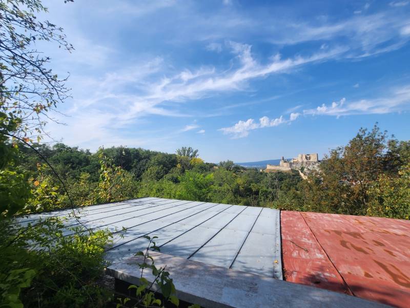 View from the Cottage in Beckov to the castle, with a panorama of greenery and blue sky.