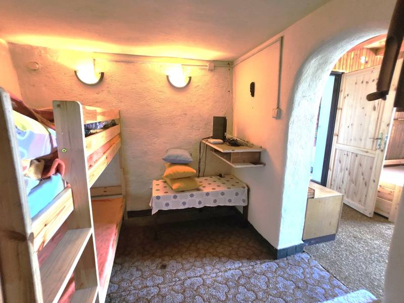 Interior of a cabin with a bunk bed, a small table, and cushions on a shelf.