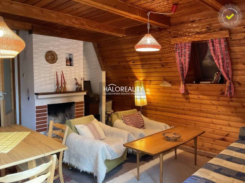 Wooden interior of a cabin with a sofa, fireplace, and dining table.