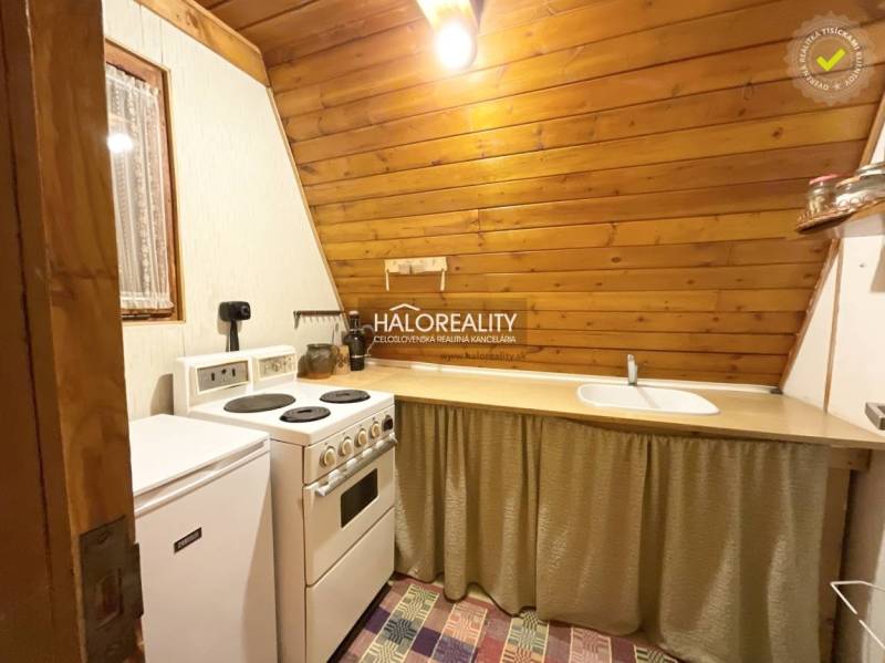 A kitchenette in a cabin with wooden paneling and simple furnishings.