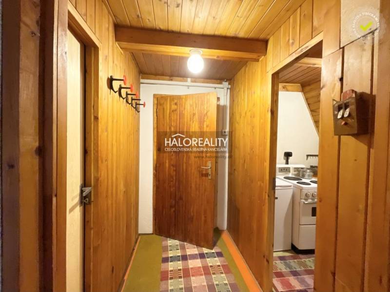 A wooden interior of a cabin with coat hooks and a kitchen on the right.