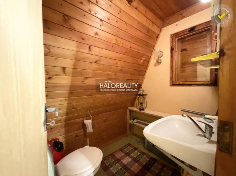 Bathroom in a cabin with wooden paneling, toilet, and sink.