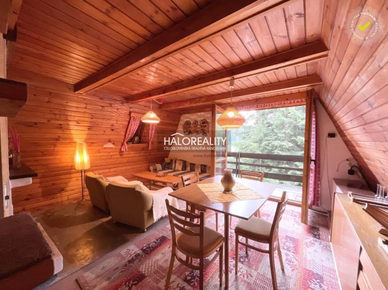 Wooden interior of a cabin with a living room, couch, and dining table.