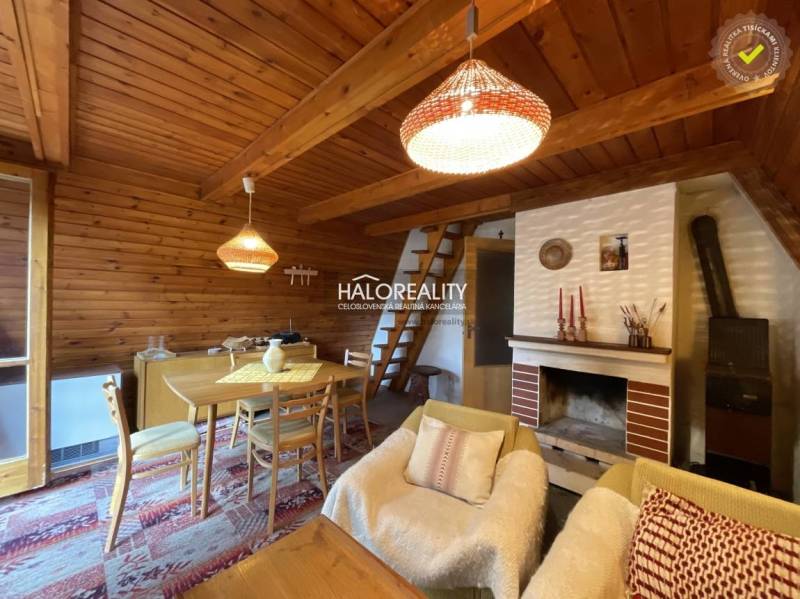 Wooden interior of a cabin with a sofa set, dining table, and fireplace.