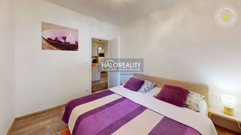 A bedroom in a 3-room apartment with purple accessories and a painting on the wall.
