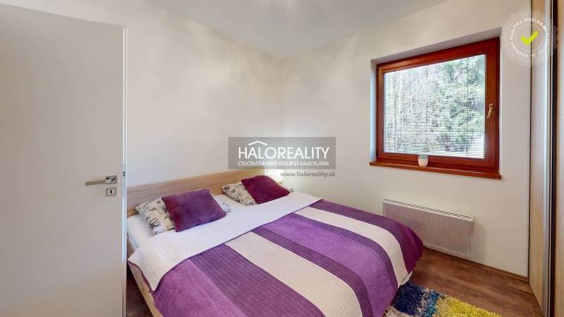 A bedroom in a 3-room apartment with colorful bedding and a large window.