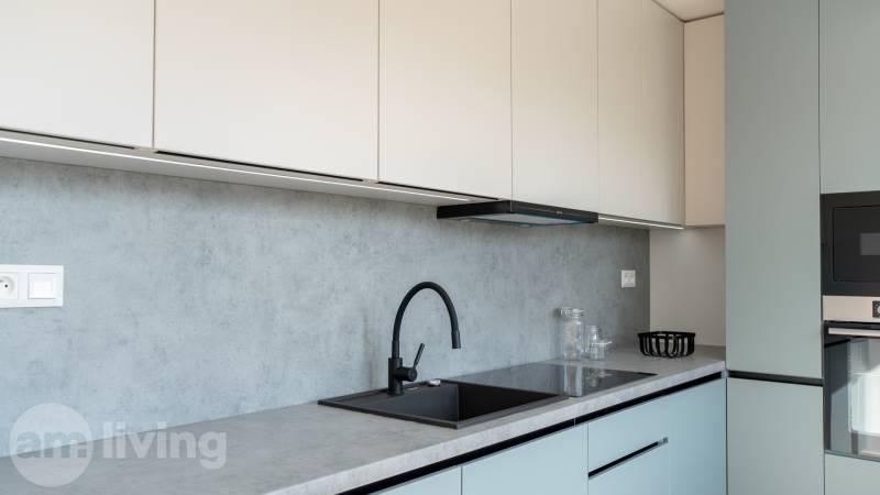 A kitchen in a 2-room apartment with a simple countertop and a black faucet.