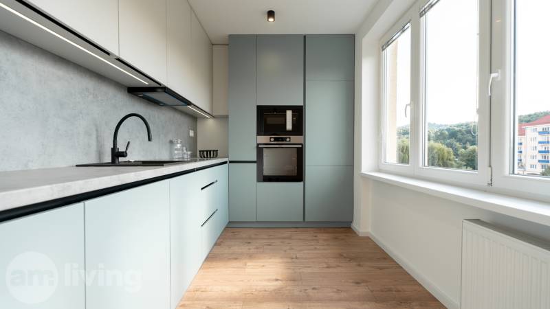 A bright kitchen in a 2-room apartment with modern appliances and a large window.