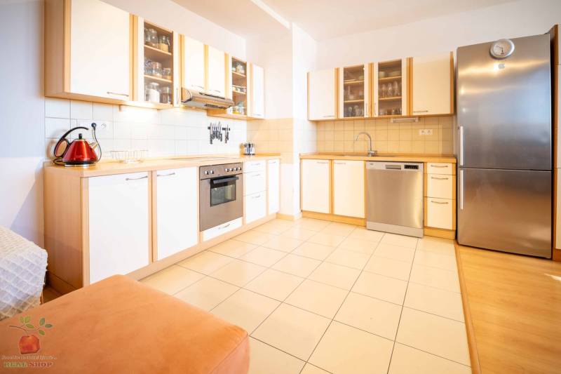 A kitchen with a wooden cabinet, a stove, and a silver refrigerator in a three-room apartment.