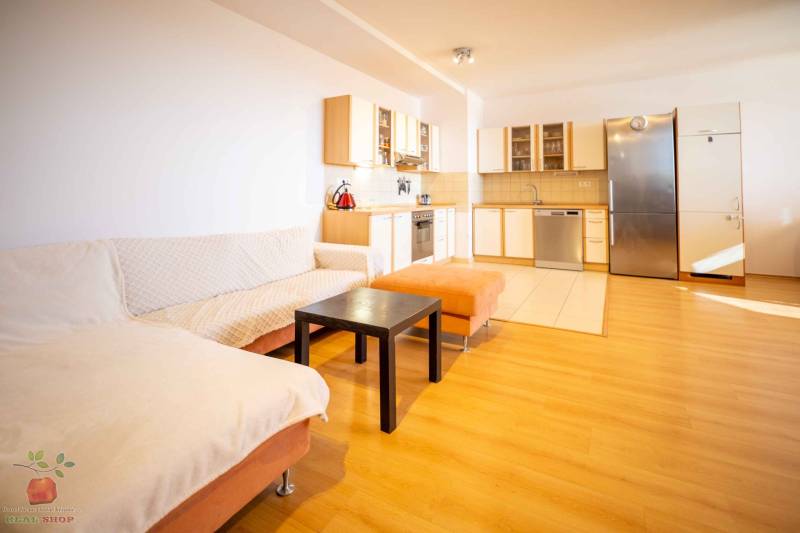 Living room with kitchen in a 3-room apartment, wooden floor and built-in kitchen unit.
