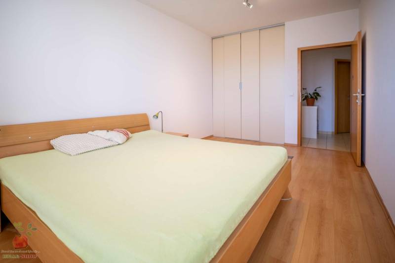 Bedroom in a 3-room apartment with a wooden bed and wardrobe, light wooden floors.