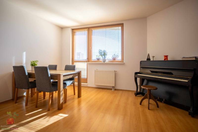 A bright room in a 3-room apartment with a piano and a dining table.