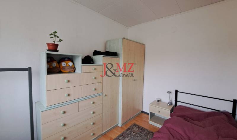 A room in a family house with furniture, a carpet, a bed, and decorations.