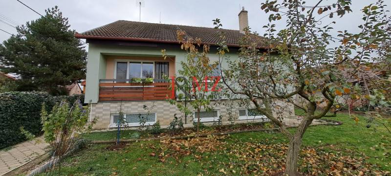 A family house in Levice with a front garden, lawn, and trees around.