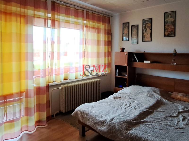 Bedroom in a family house with curtains, paintings, and a radiator.