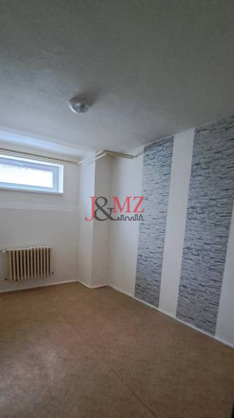 A room in a family house with a radiator, gray walls, and a small window.