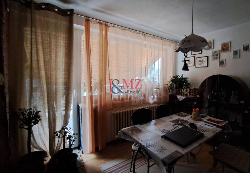 Dining area in a family house with curtains, decorations, and a table with chairs.