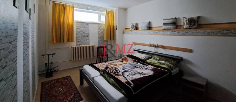 A bedroom in a family house with a carpet, a bed, and yellow curtains.