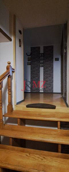A staircase in a family house with a wooden railing and a decorative wall.