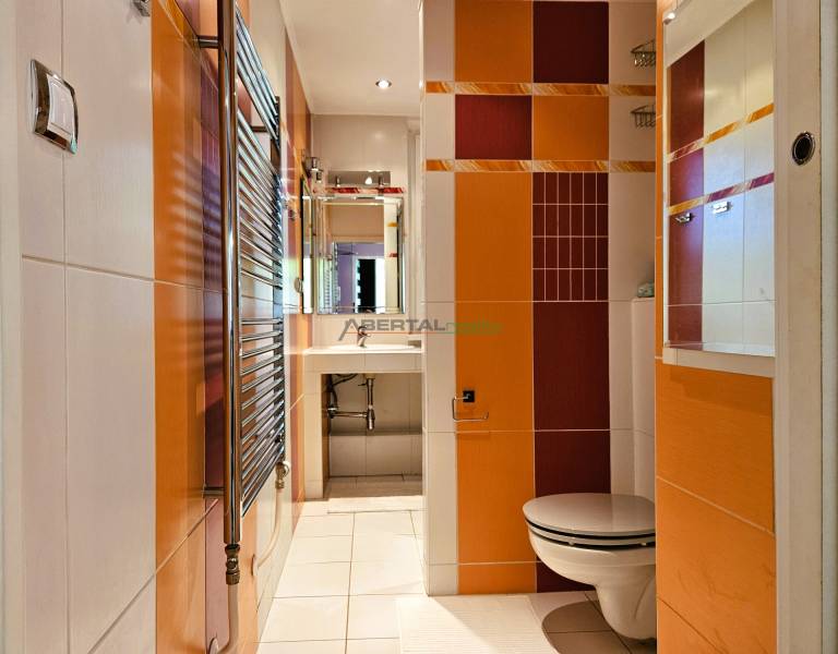 Bathroom in a 2-room apartment with colorful tiles, a sink, and a toilet.